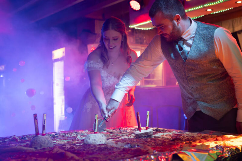 Das Brautpaar schneidet auf der Hochzeitsparty die Hochzeitspizza an